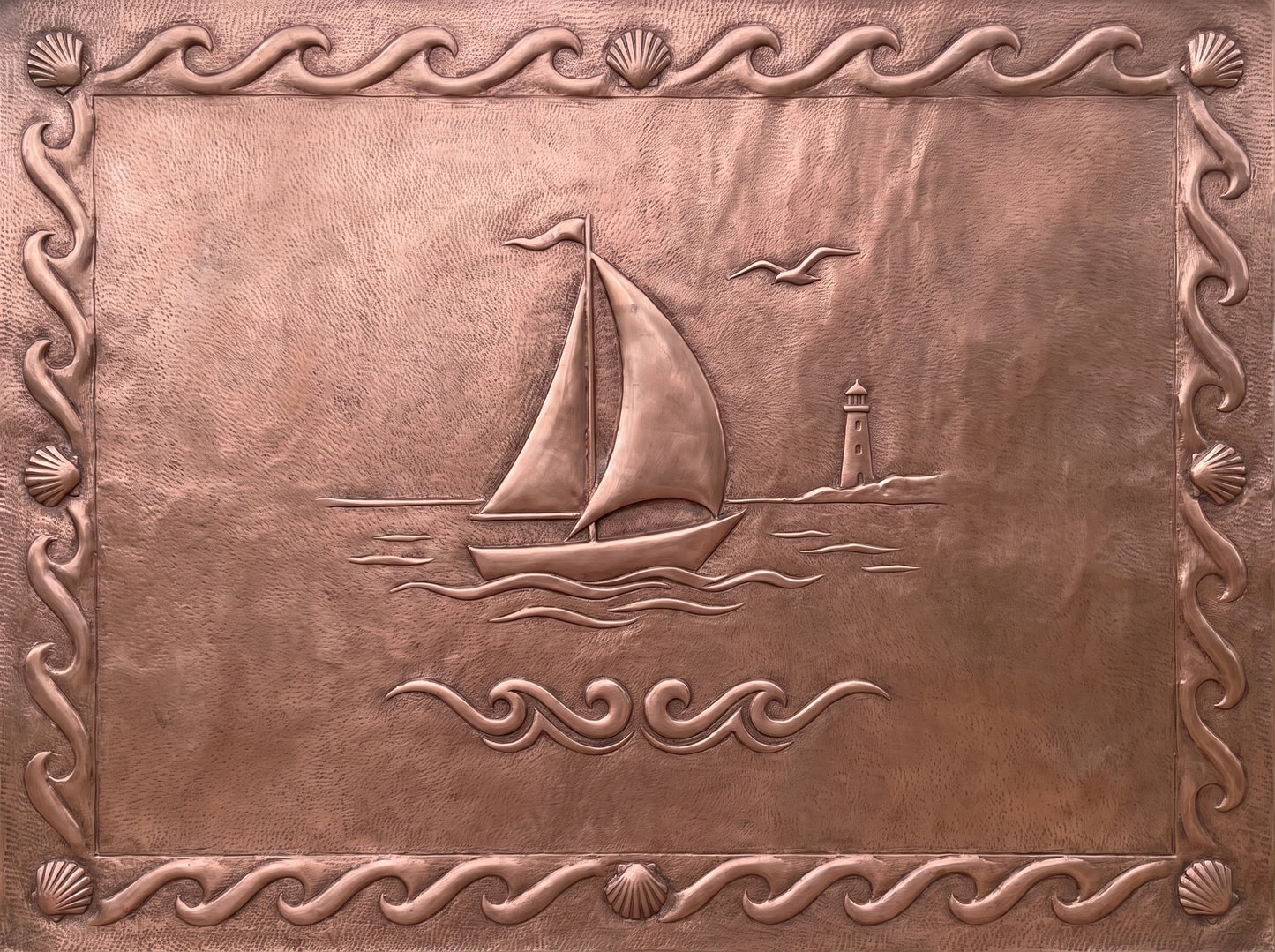 Handcrafted copper kitchen backsplash with sailboat, lighthouse, and decorative seashell border