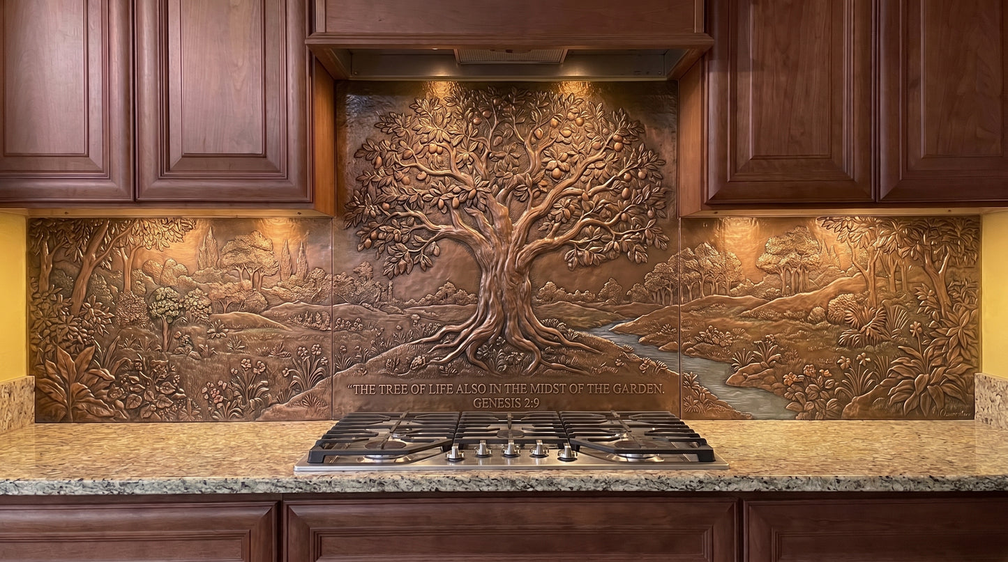 Handcrafted Tree of Life in Eden copper kitchen backsplash inspired by Genesis 2:9, featuring a large Tree of Life in a lush Garden of Eden landscape with dense vegetation, smaller trees, rolling ground, and a stream extending across the copper backsplash behind the range and under the cabinets.