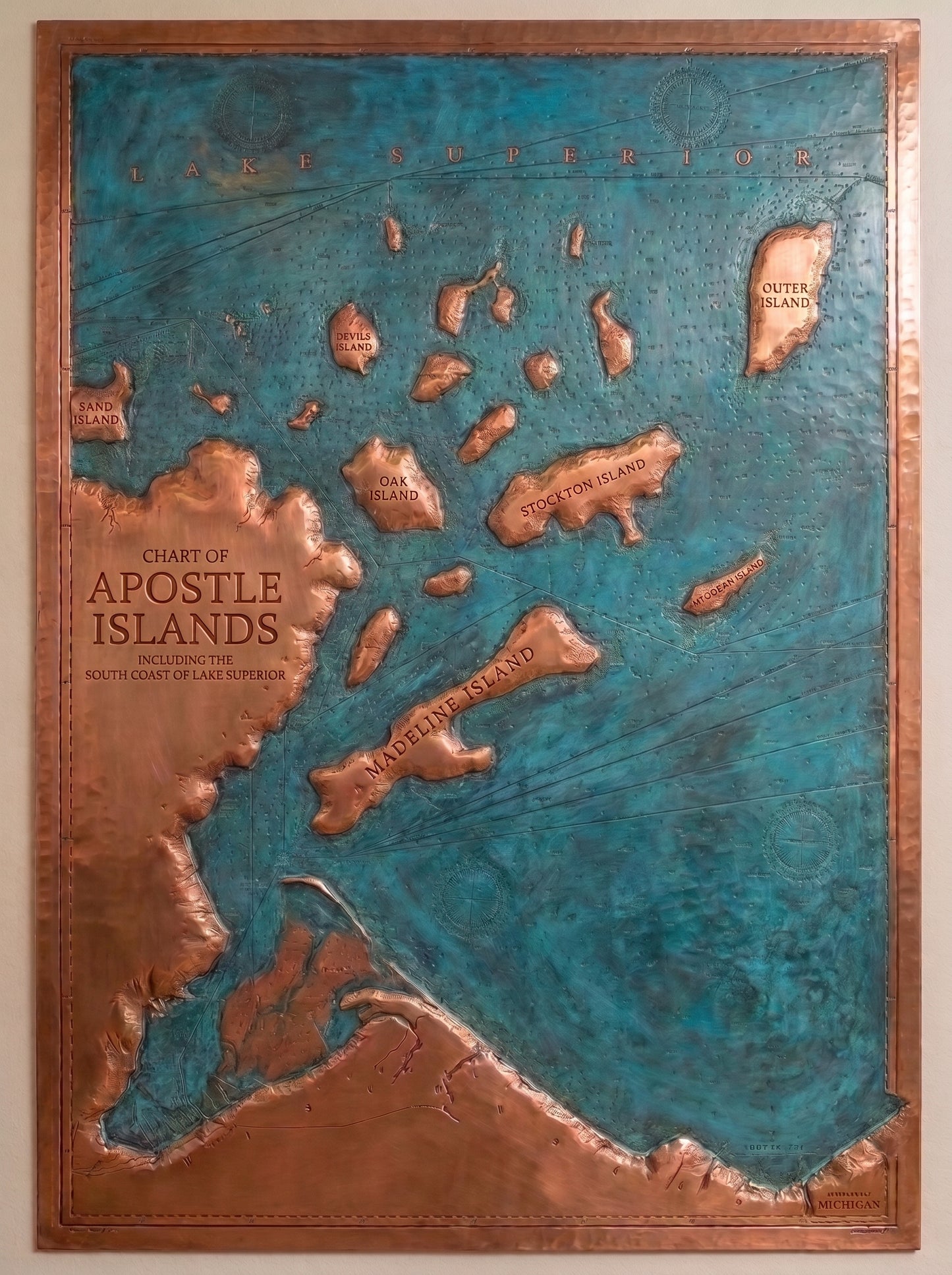 Hand-hammered lake map wall art made from real copper, featuring a raised relief map of the Apostle Islands and Lake Superior with copper shorelines and islands, blue-green patina water, nautical chart details, place names, and a copper border.