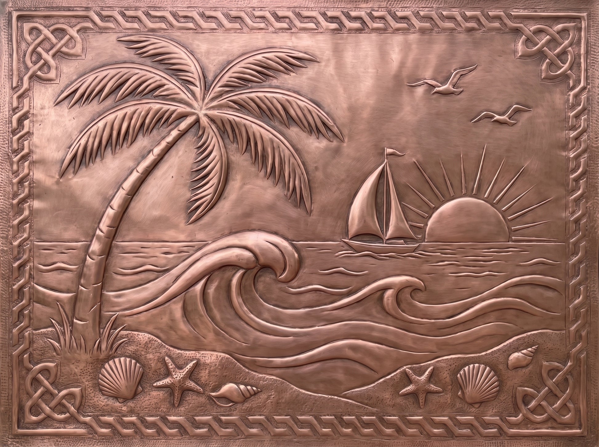 Handcrafted copper kitchen backsplash with palm tree, ocean waves, sailboat, sunset, and seashells