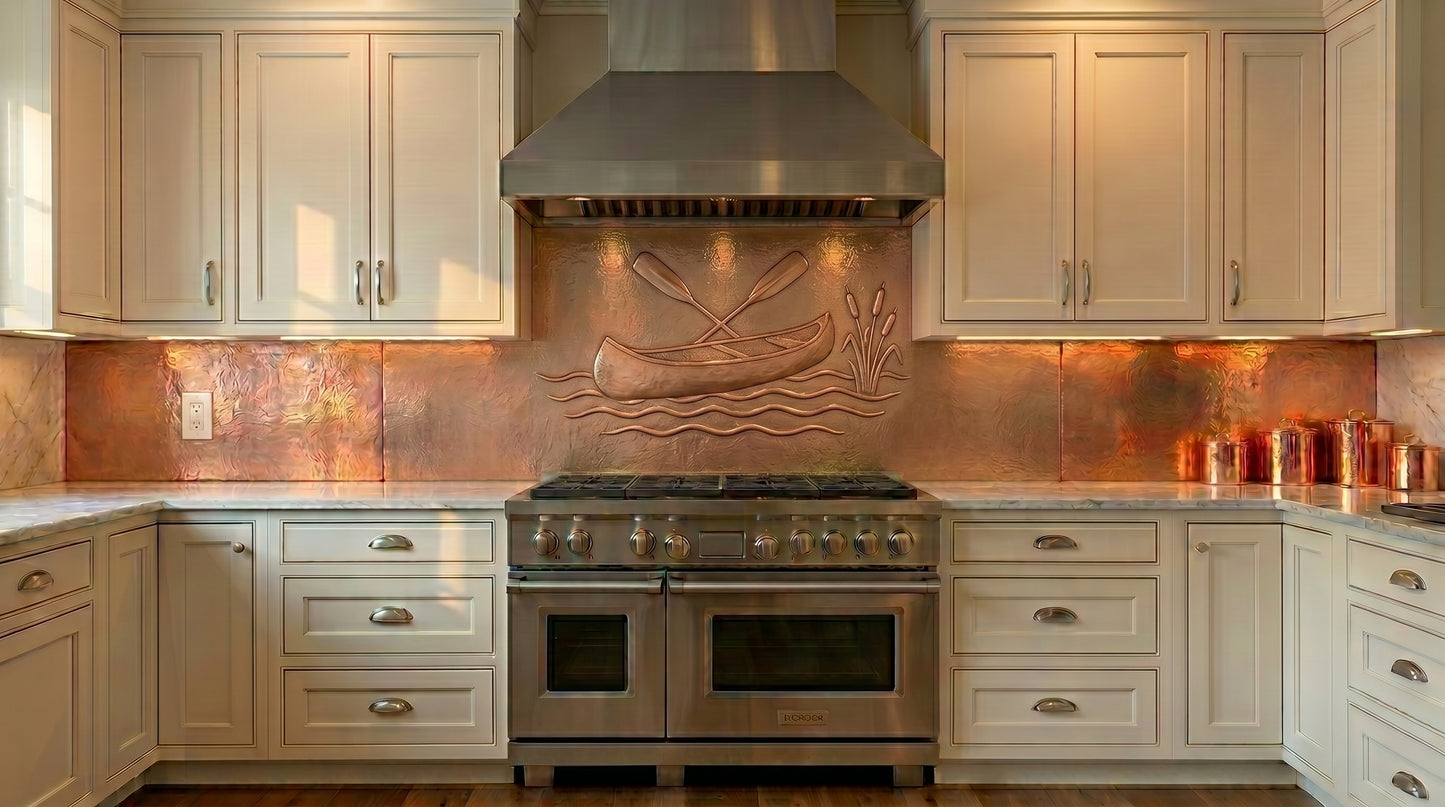 Handcrafted copper hood backsplash featuring a raised canoe, crossed paddles, flowing water, and cattail relief. Custom copper range hood backsplash made from real copper for lake houses, cabins, lodges, rustic homes, and outdoor-inspired kitchens. Available in custom sizes and finishes.