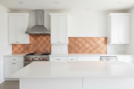 Three separate hand-hammered copper backsplash panels with diamond lattice repoussé design installed behind an off-center range — tall center panel with narrower left side panel and wider right side panel