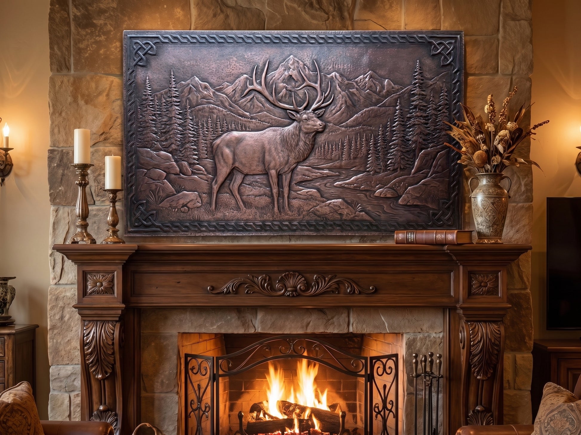 Handcrafted Rocky Mountain Elk copper panel displayed above a large stone fireplace, featuring a bull elk in raised relief surrounded by pine trees, rugged mountain peaks, rocks, and a winding stream, framed with a detailed Celtic-inspired border.