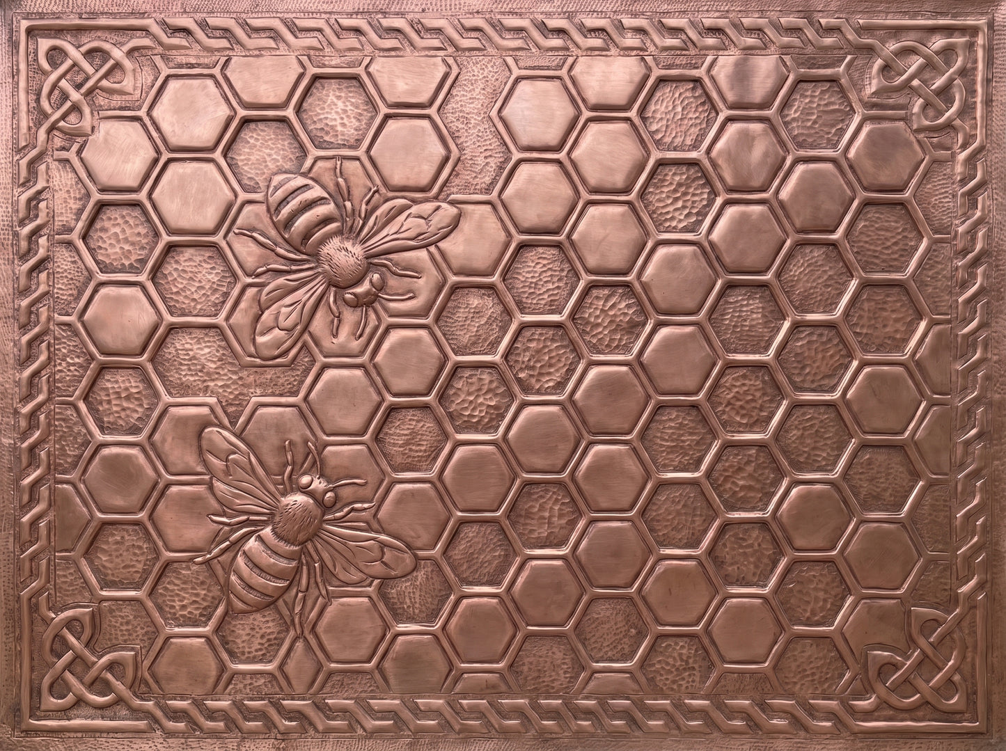 Handcrafted copper kitchen backsplash with raised honeybees and honeycomb pattern