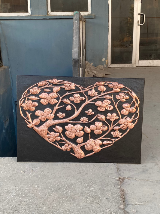 Decorative heart-shaped metal art piece with floral design on a concrete floor.