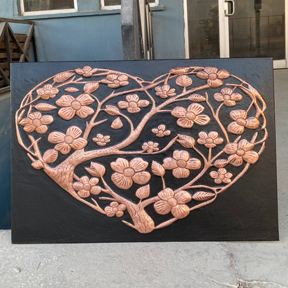 Decorative metal wall art with floral design on a black background, outdoors.
