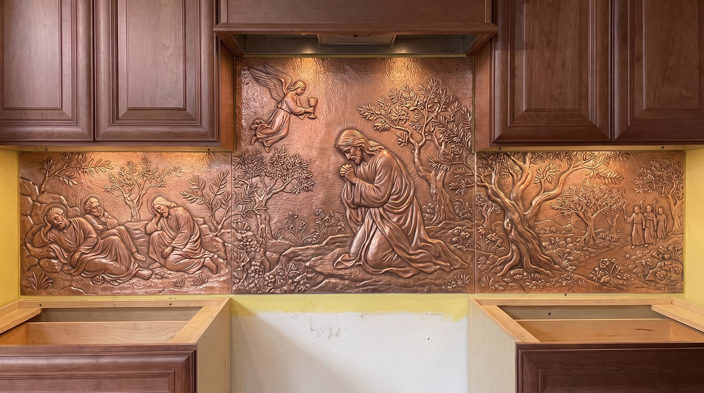 Agony in the Garden copper kitchen backsplash depicting Jesus praying in the Garden of Gethsemane, with disciples, approaching figures, olive trees, garden vegetation, and landscape details telling the biblical Gethsemane story in raised metal relief across the range wall.
