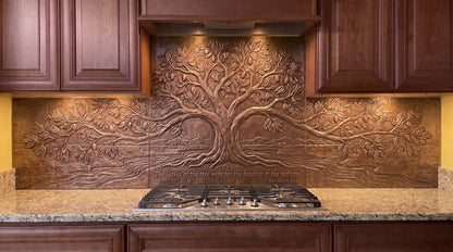 Leaves of the Tree of Life copper kitchen backsplash inspired by Revelation 22:2, featuring a large Tree of Life with a broad leafy canopy, sweeping branches, flowing water, and landscape details formed in raised relief across the range-wall backsplash.