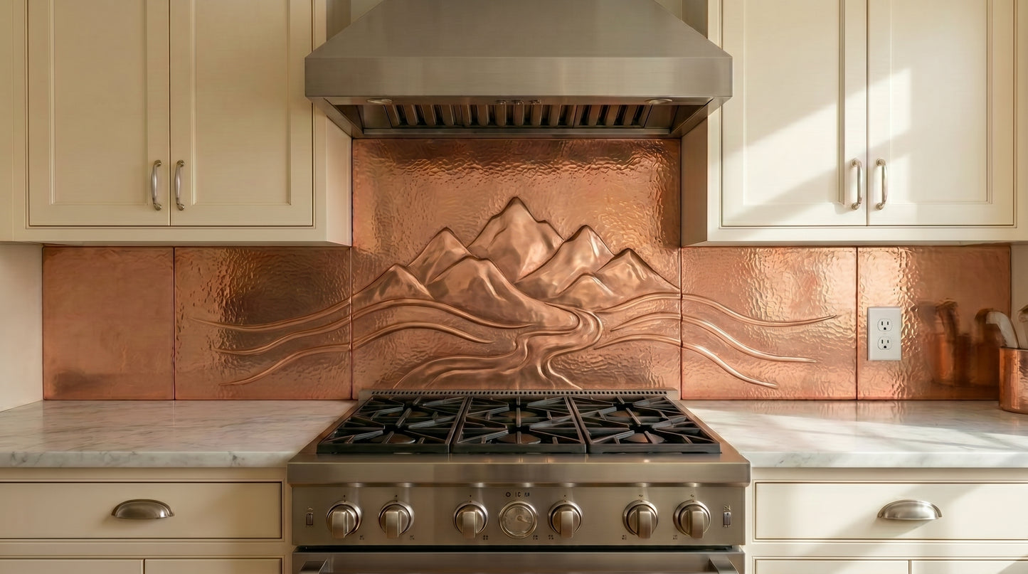 This mountain copper kitchen backsplash features a hand-hammered mountain landscape flowing across a custom copper backsplash installation.