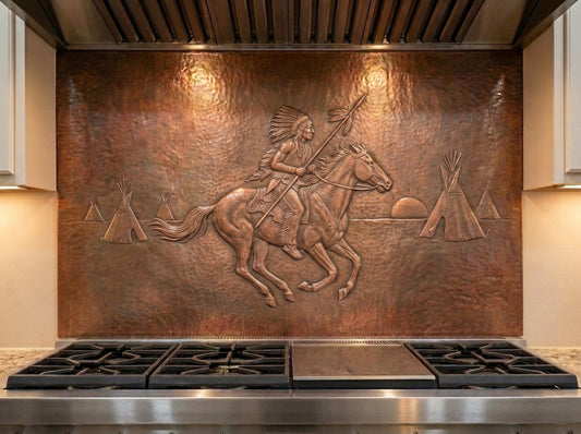 Handcrafted copper stove backsplash installed behind a professional range, featuring a Native American rider on horseback holding a spear in raised relief, with a feather headdress, tipis, setting sun, and hand-hammered copper background in a Western kitchen.