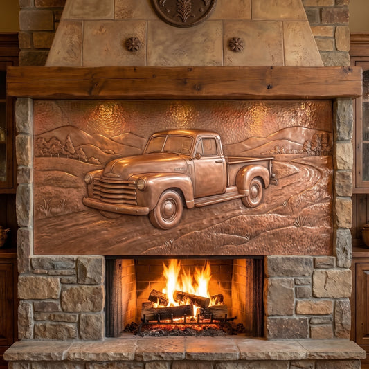 Hand-hammered copper pickup truck wall art displayed above a fireplace, featuring a classic vintage pickup driving on a winding country road with open fields, trees, rolling hills, and clouds, with the truck and landscape formed in raised copper relief.