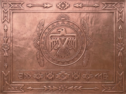 Handcrafted Thunderbird Southwestern copper backsplash with a large raised Thunderbird at the center, surrounded by detailed feathers, arrows, geometric symbols, sunburst forms, and a patterned border worked by hand into the metal surface.