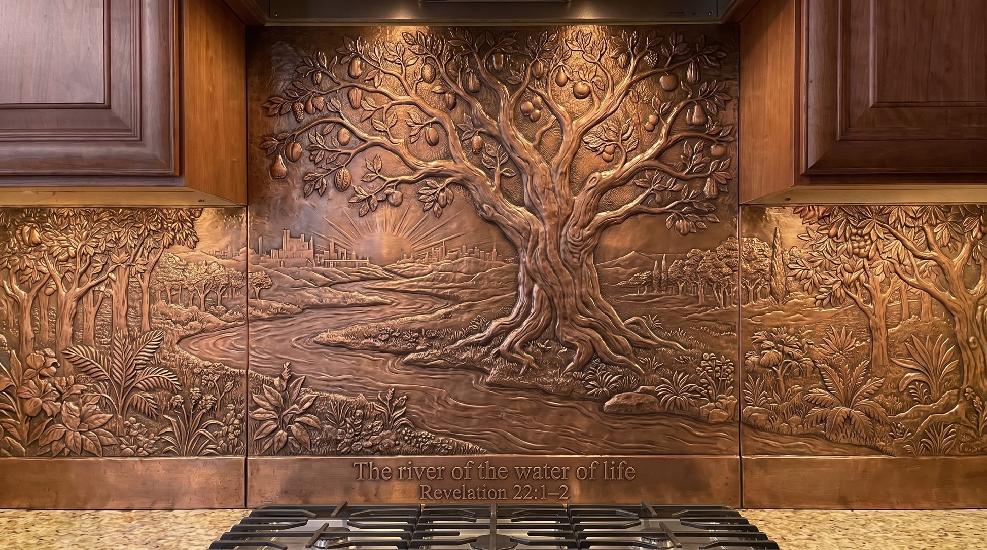 Handcrafted Tree of Life & River of Life copper kitchen backsplash inspired by Revelation 22:1–2, with a large Tree of Life behind the range and a winding river, trees, foliage, and landscape arranged across the full copper backsplash under the kitchen cabinets.