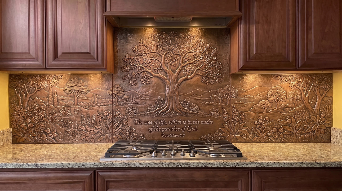 Handcrafted Tree of Life in Paradise copper kitchen backsplash inspired by Revelation 2:7, with a large Tree of Life behind the range and a garden of flowering plants, foliage, smaller trees, and landscape details extending across the copper backsplash under the cabinets.