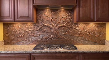 Twelve Fruits of the Tree of Life copper kitchen backsplash inspired by Revelation 22:2, featuring a large fruit-bearing Tree of Life beside flowing water with abundant fruit, foliage, and landscape details formed in raised relief across the range-wall backsplash.