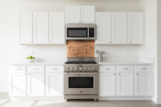 Wide shallow hand-hammered copper backsplash panel with acanthus scroll repoussé design installed in the space between stove and over-the-range microwave