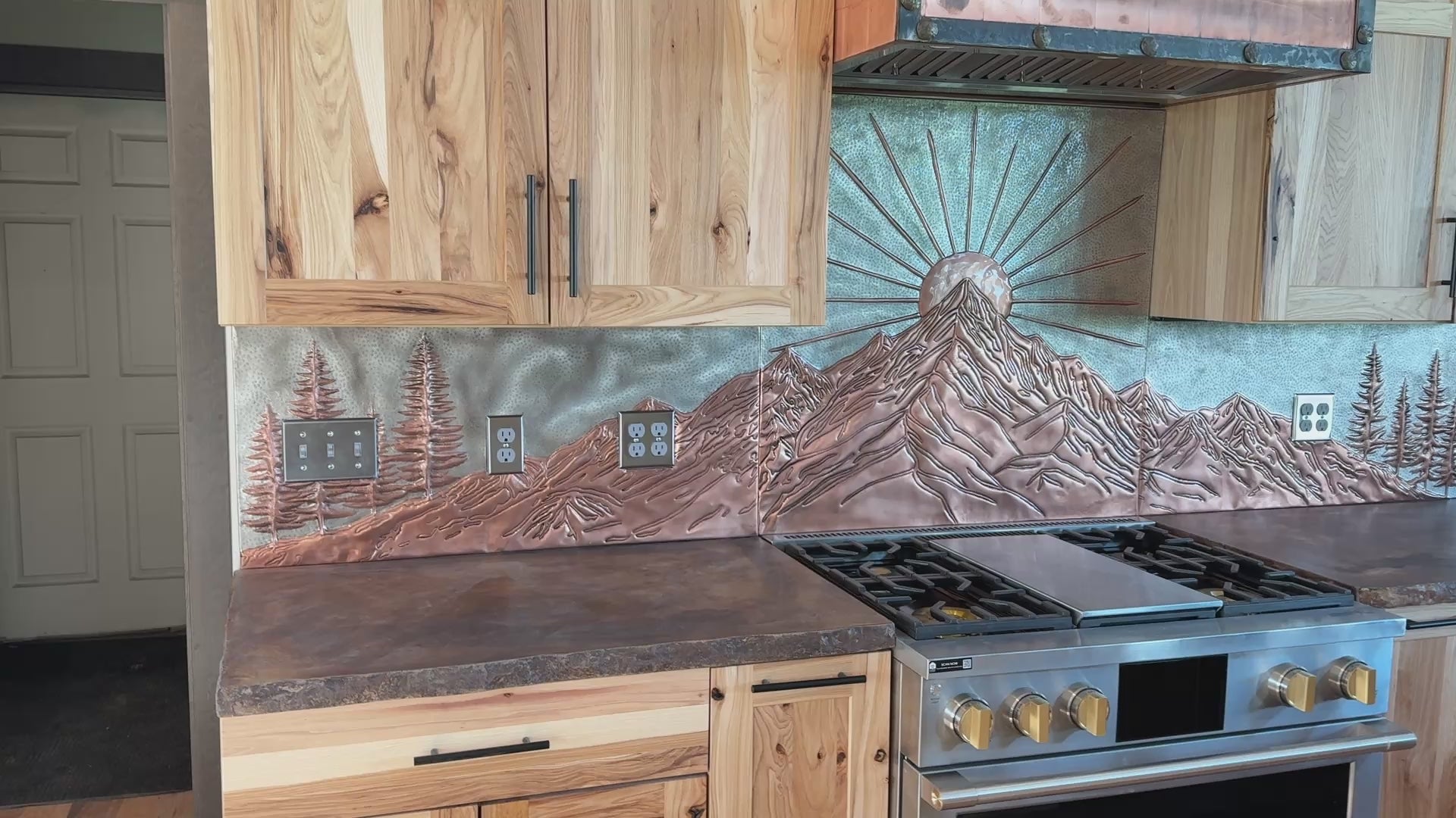 Video showing the hand-hammered Mountain Sunrise copper kitchen backsplash set with raised relief details, full-wall layout, and custom multi-panel design.